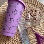 lila színű pohár szívószállal, üvegpohárral és könyvjelzővel hangjegy mintával