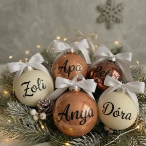 Limitált kiadású névre szóló karácsonyfadíszek elefántcsont, rosé bronz és étcsokoládé árnyalatú üveggömbökön, fehér masnival díszítve.